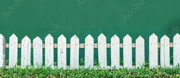 Fototapeta Front view of a short white picket fence made of simple painted wood on a green background serving as a design element with copy space image