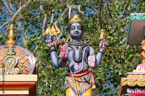 Fototapeta Figure of Shiva with a trident and the dome of a Hindu temple in India.