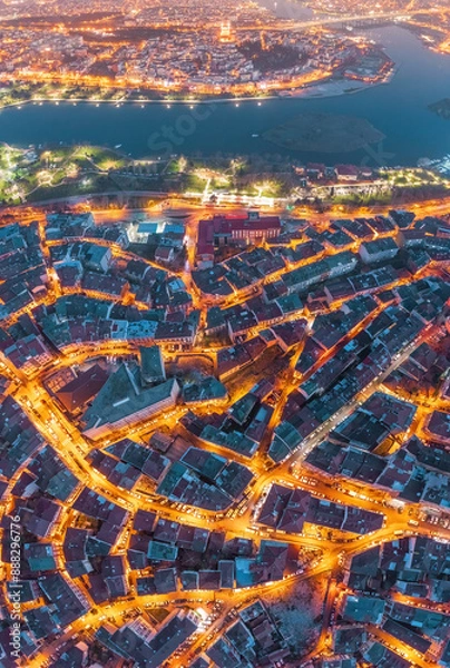 Fototapeta Aerial view of city of Istanbul at night with intricate street patterns and illuminated buildings. In the background, Bosphorus separates a historic neighborhood from another brightly lit part of city