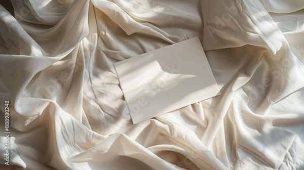Fototapeta Blank paper card sheets with copy space on wrinkled bed blanket cloth with aesthetic warm sunlight shadows Flat lay top view