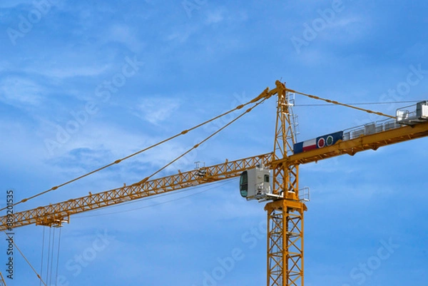 Obraz Construction tower crane are working. close up view on blue sky background.
