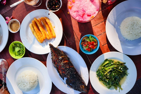 Fototapeta Rice, grilled fish, vegetables and chili sauce as well as various dishes on the table. Asian food