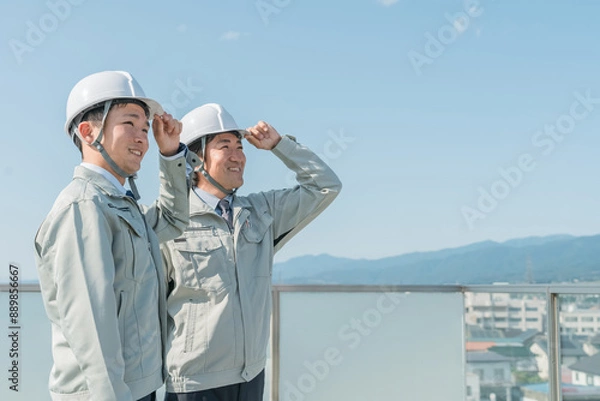 Fototapeta 青空の中に立つ作業服を着た作業員（建設・建築・設計・不動産・土木・工事・現場監督・運送）
