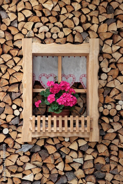 Obraz Window with pink flowers surrounded by a stack of firewood
