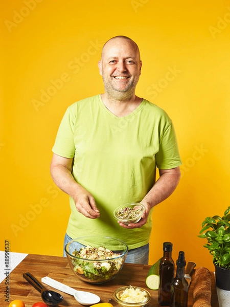 Obraz Middle-aged man cook fresh salad