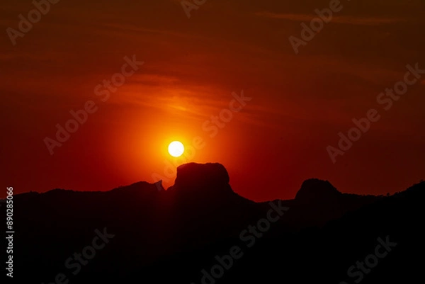 Obraz View of Pedra do Baú in silhouette with the sun almost touching it during sunrise