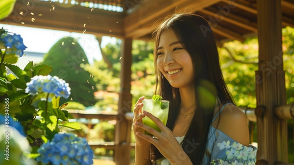 Fototapeta 夏の庭で冷たい緑茶を楽しむ若い女性