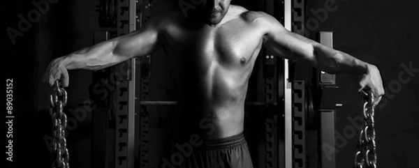 Fototapeta Close up of young muscular man lifting weights . Black and White High Contrast in Studio