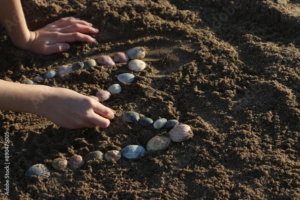 Obraz Niño escibiendo con ostras sobre la arena