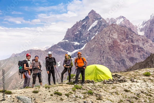 Obraz Alpine climbers team and camp Group of five people men and women staying along green camping tent on majestic mountain landscape of deserted Asian area
