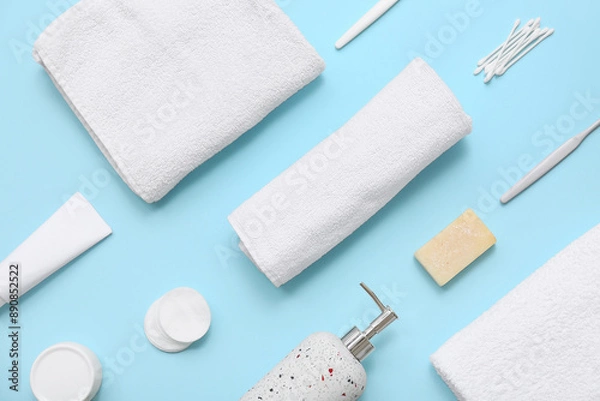 Fototapeta Composition with clean soft towel and different bath supplies on blue background, closeup