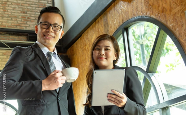 Fototapeta Executive business managers office team working using 
computer drinking hot coffee. Two mid aged colleagues company board after discussing digital strategy at modern meeting room. Copy space.