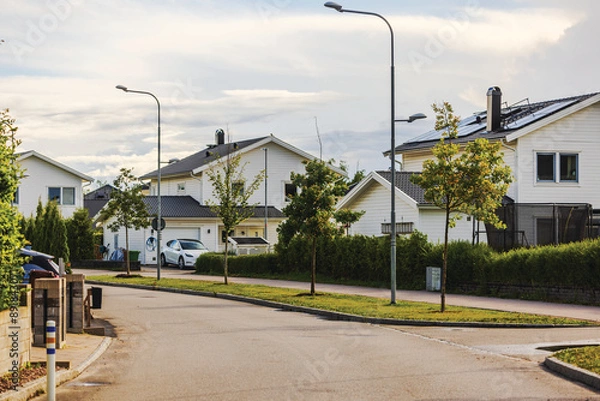 Fototapeta Picturesque European village with modern villas, asphalt road, and solar panels on rooftops, blending elegance with sustainability. Sweden.