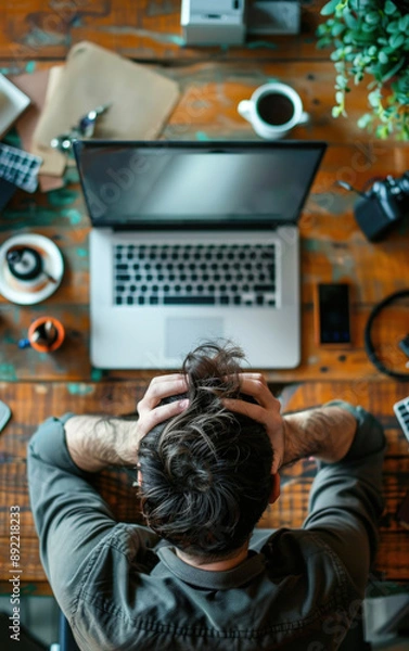 Fototapeta Man at computer desk hands on head stressed office background daylight high angle