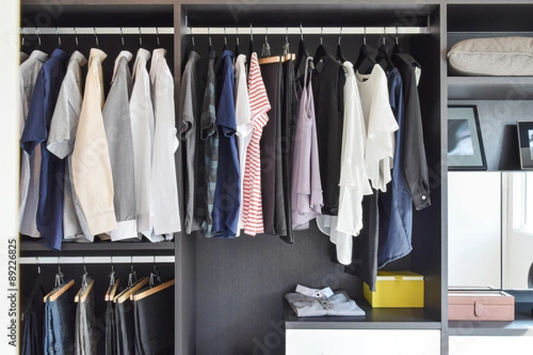 Fototapeta modern closet with row of cloths hanging in black wardrobe