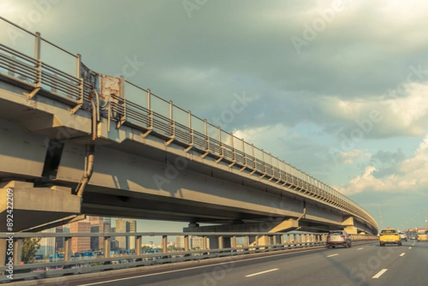 Fototapeta A long bridge with a yellow car driving on it