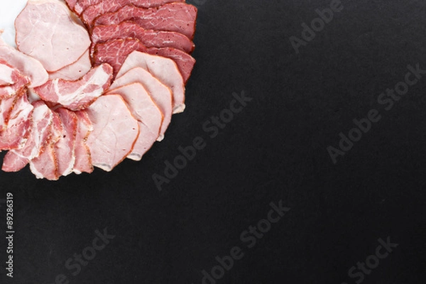 Obraz cutting ham with vegetables assortment on black background