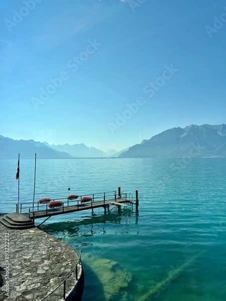 Obraz View of Lake Geneva with the Alps in the background and a  wooden boat pier in the foreground.  A sunny day with no people and copy space. 