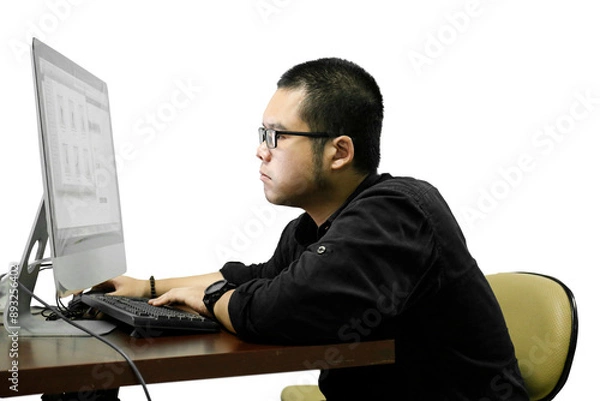 Fototapeta an Asian man wearing glasses is seriously working using a computer on a white background