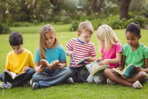 Fototapeta Classmates sitting in grass and reading books