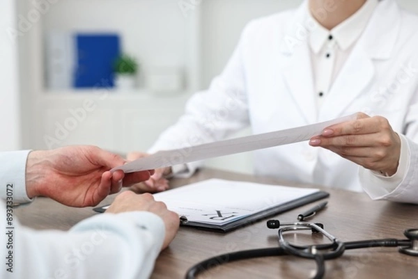 Obraz Doctor giving prescription to patient at wooden table in clinic, closeup