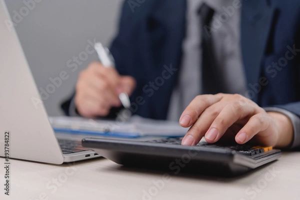 Fototapeta Professional Businessman Calculating Budget with Calculator and Laptop, Financial Planning in Corporate Setting