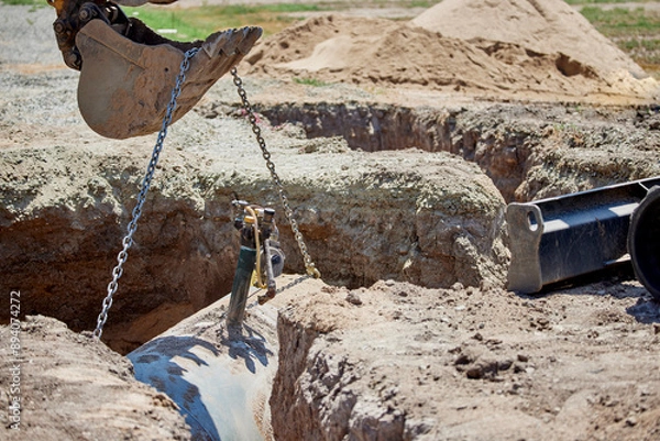 Obraz Preparing to lift out a buried propane tank with the bucket on an excavator