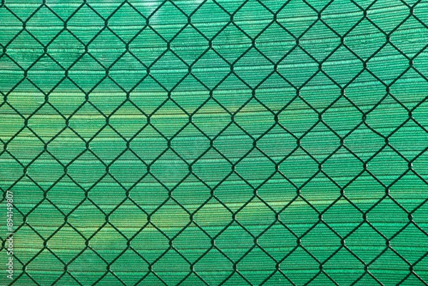 Fototapeta Chain link fence with green mesh background texture, sports field
