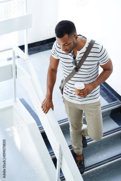Fototapeta Black man, coffee and college student walking on steps for break, lecture or next class in building. African male person, espresso and cup for beverage on campus in university to travel downstairs