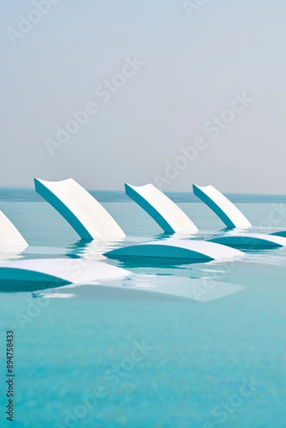 Obraz Pool chairs in a beautiful blue pool overseeing the sea