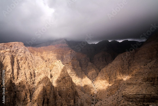 Obraz sun peaking through stormy clouds in UAE mountains