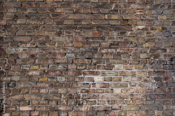 Fototapeta brick wall background with names scratched