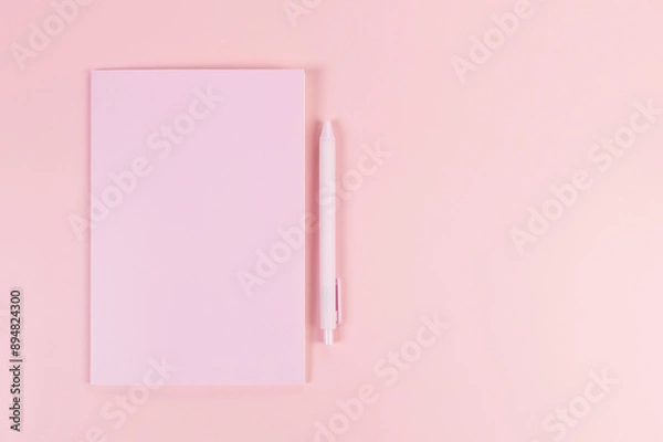 Fototapeta Top view of pink notebook, pink pen on pink background. School, office wallpaper. Flat lay, copy space.