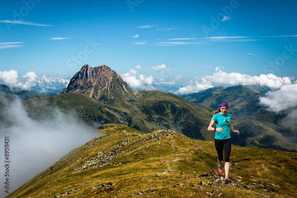 Fototapeta happy girl running in the mountains scenery with blue sky and epic view