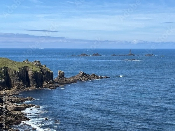 Fototapeta A beautiful cliff rises majestically above the ocean, its rugged rocks contrasting with the deep blue waters below. 