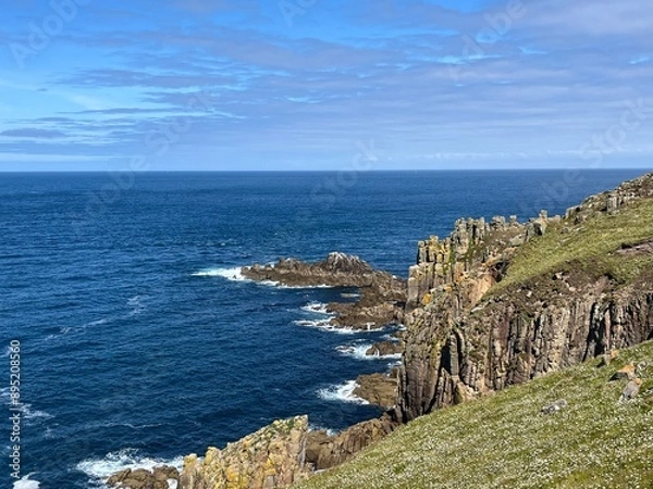 Fototapeta A beautiful cliff rises majestically above the ocean, its rugged rocks contrasting with the deep blue waters below. 