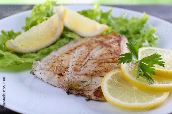 Obraz Dish of fish fillet with lettuce and lemon on plate close up