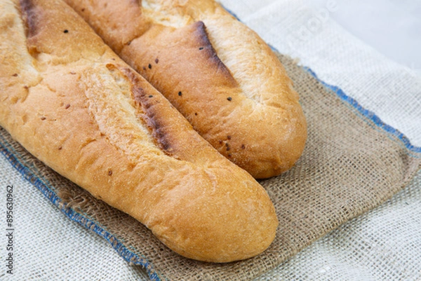 Fototapeta French baguette bread sliced ​​on a wooden cutting board against a white background. Preparing the iftar table.