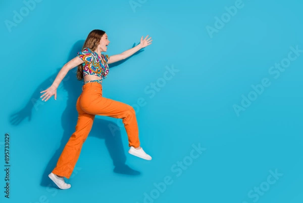 Fototapeta Full size photo of nice young girl run empty space wear top isolated on blue color background
