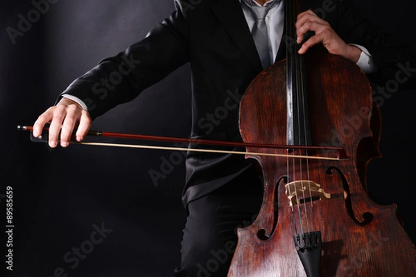 Fototapeta Man playing on cello on dark background