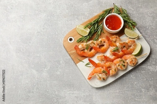 Fototapeta Skewers with delicious grilled shrimps served on grey table, top view. Space for text
