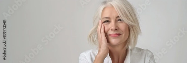 Obraz An elderly woman with graceful gray hair exudes joy and confidence, smiling peacefully in a white shirt. Her pose radiates contentment and elegance, portraying a positive lifestyle