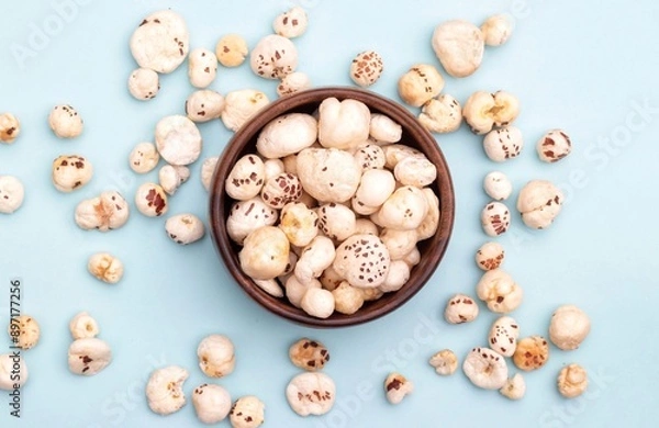 Obraz Top View of Makhana or Fox Nut in a Wooden Bowl Isolated on Light Blue Background with Copy Space, Also Known as Lotus Seed Pop, Euryale Ferox or Gorgon Nut