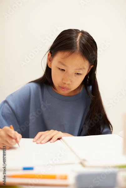 Fototapeta 夏休みの小学生の女の子が家で宿題をする姿