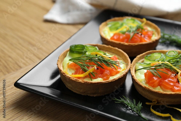 Fototapeta Delicious canapes with salmon on wooden table, closeup