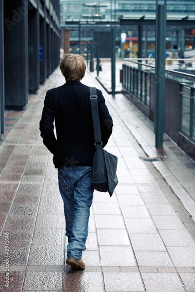 Fototapeta Teenage boy walking away from camera in street