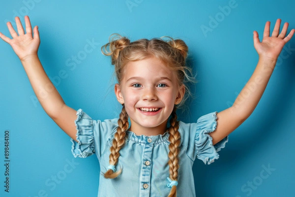 Fototapeta Portrait of a nice young girl with her arms thrown back, causing her hair to fly, wearing a top and isolated on a blue background. The scene captures a vibrant and joyful moment. AI generated.