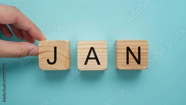 Fototapeta January word on wooden block in month date concept with light blue background.