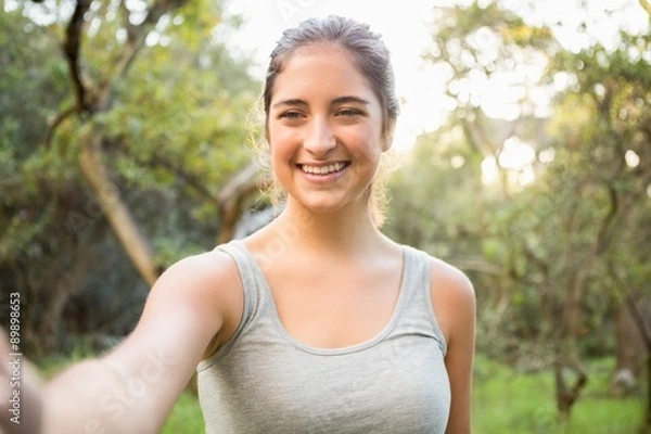 Fototapeta Smiling athletic brunette taking selfie
