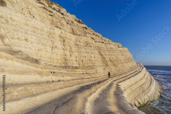 Fototapeta Tourist walking on rock cliff Stairs of the Turks or Scala dei Turchi at mediterranean coast during golden hour at sunset, Realmonte, Sicily, Italy